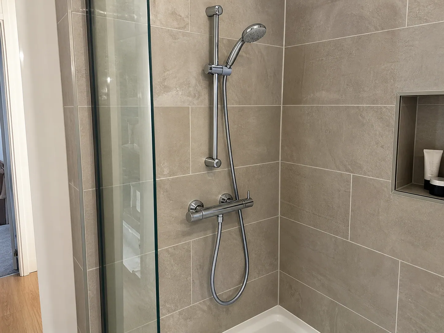 AI-generated illustration: Chrome shower mixer, hose and shower enclosure