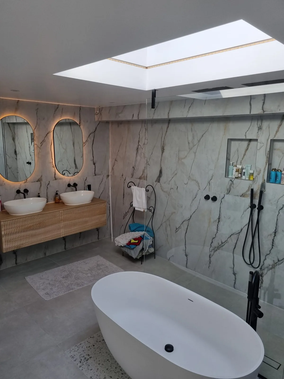 Bathroom under the skylight: Two basins, lit mirrors, a freestanding bath and a walk-in shower.